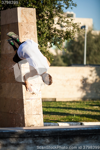 Image of Young man performing parkour in the city