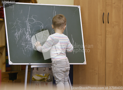 Image of Little boy drawing on a chalkboard at kindergarten