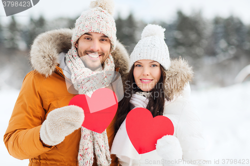 Image of happy couple with red hearts over winter landscape