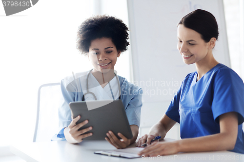 Image of happy doctors with tablet pc meeting at hospital