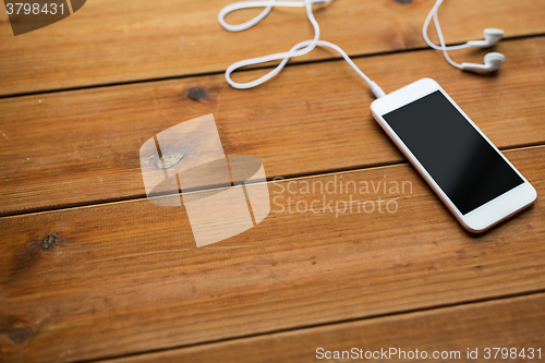 Image of close up of blank smartphone and earphones on wood