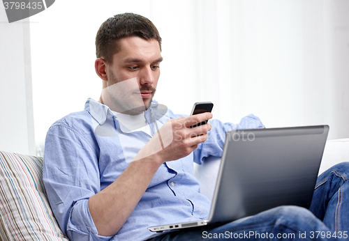 Image of man with smartphon and laptop computer at home