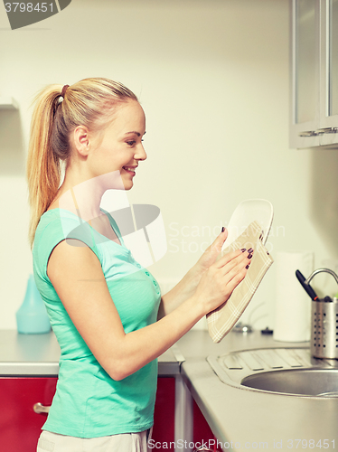 Image of happy woman wiping dishes at home kitchen