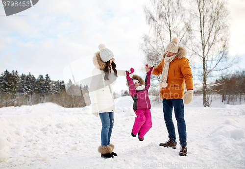 Image of happy family in winter clothes walking outdoors