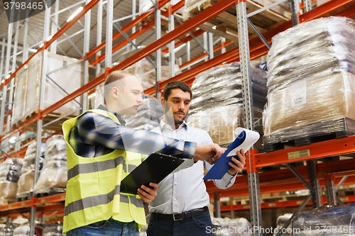 Image of worker and businessmen with clipboard at warehouse