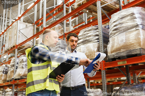 Image of worker and businessmen with clipboard at warehouse