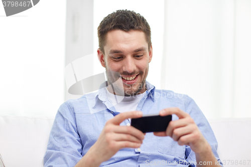 Image of happy man with smartphone at home