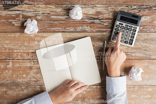 Image of close up of hands with calculator and notebook