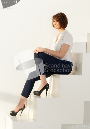 Image of Smiling businesswoman sitting on steps with eyes closed