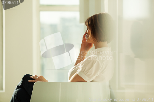 Image of Side view of smiling businesswoman talking on phone