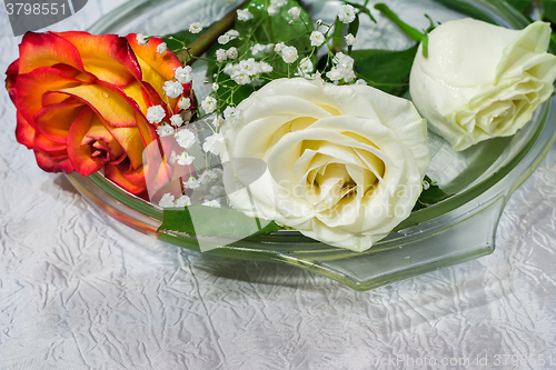 Image of The roses on the table on a glass dish.