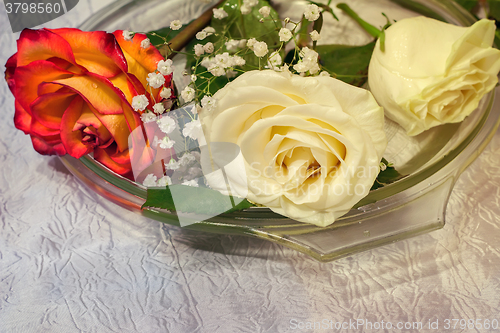 Image of The roses on the table on a glass dish.
