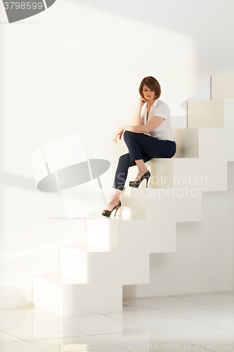 Image of Adult businesswoman sitting on steps and looking down