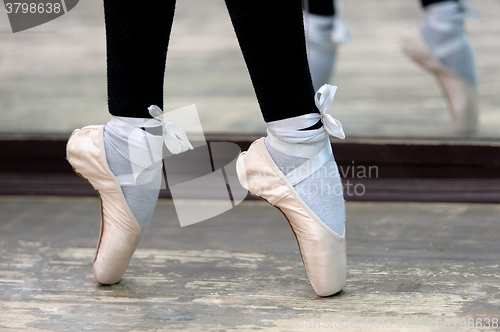 Image of Close up view to ballerinas legs in pointes on wooden floor