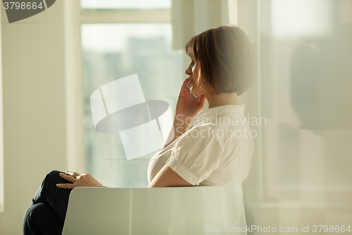 Image of Side view of businesswoman talking on phone