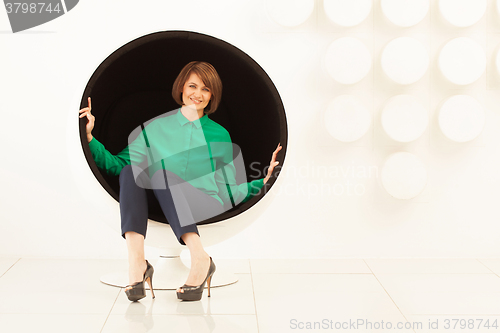 Image of Elegant woman sitting on spherical chair