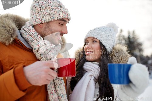 Image of happy couple with tea cups over winter landscape