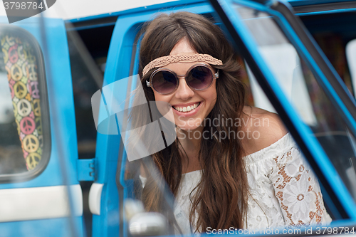 Image of smiling young hippie woman in minivan car