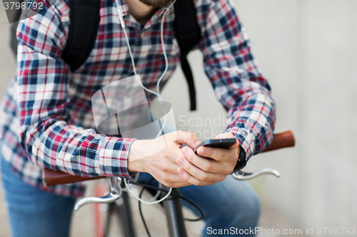 Image of hipster man in earphones with smartphone and bike