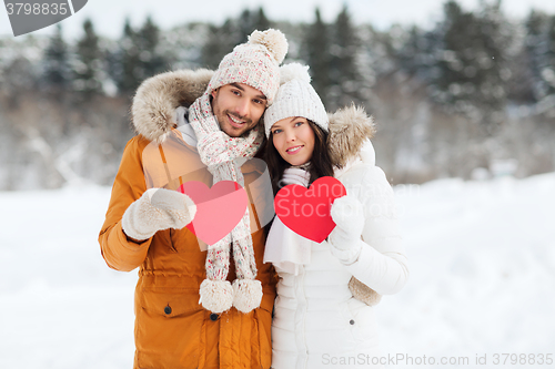 Image of happy couple with red hearts over winter landscape