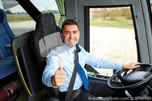 Image of happy driver driving bus and snowing thumbs up