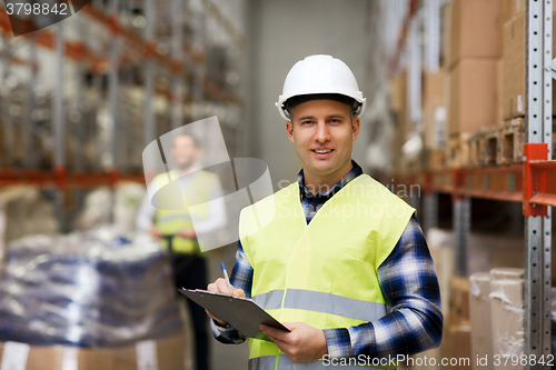 Image of man with clipboard in safety vest at warehouse