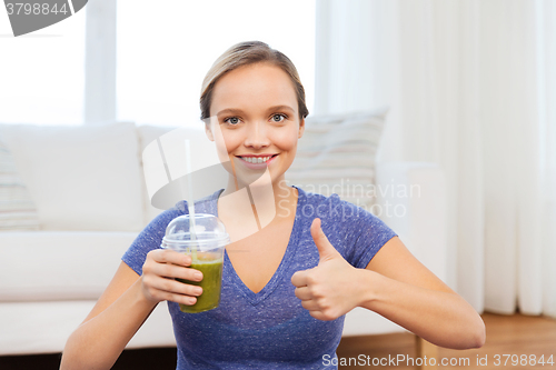 Image of happy woman with cup of smoothie showing thumbs up