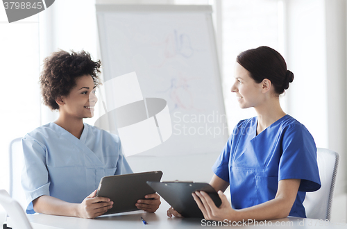 Image of happy doctors with tablet pc meeting at hospital