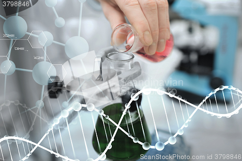 Image of close up of scientist filling test tubes in lab