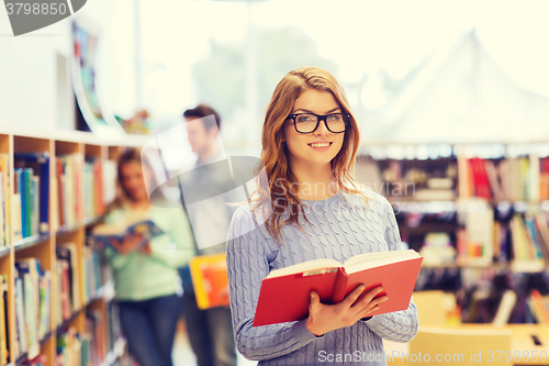 Image of happy student girl or woman with book in library