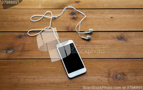 Image of close up of blank smartphone and earphones on wood