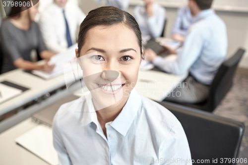 Image of group of smiling businesspeople meeting in office