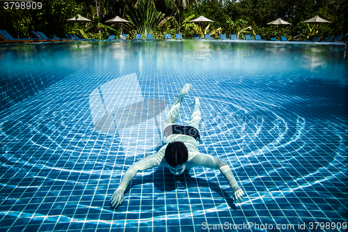 Image of Man floats underwater in pool