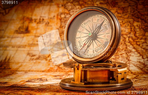 Image of Vintage compass lies on an ancient world map.