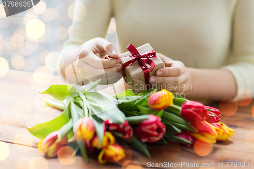 Image of close up of woman with gift box and tulip flowers