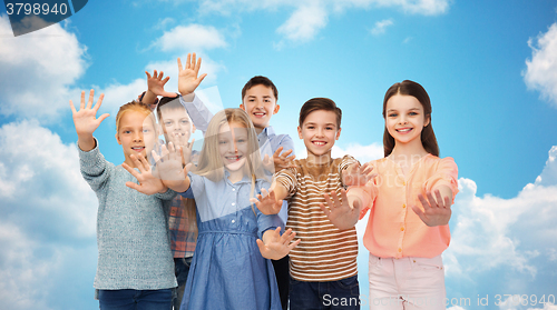 Image of happy children waving hands over blue sky