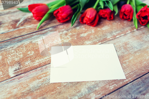 Image of close up of red tulips and blank paper or letter