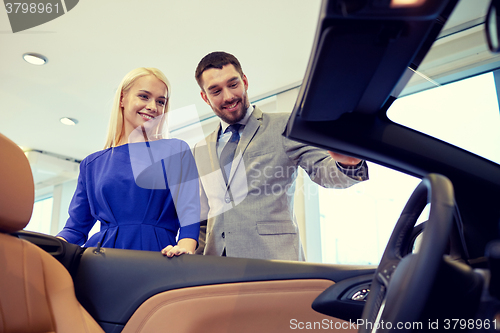 Image of happy couple buying car in auto show or salon