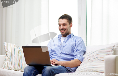 Image of smiling man working with laptop at home