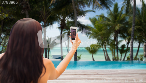 Image of young woman taking selfie with smartphone