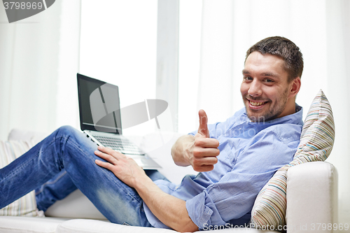 Image of smiling man working with laptop at home