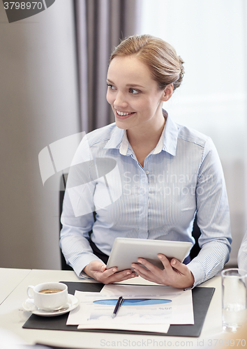 Image of smiling woman holding tablet pc computer in office