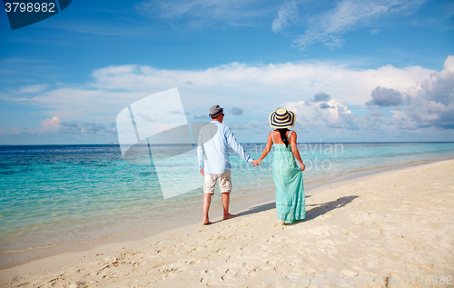 Image of Vacation Couple walking on tropical beach Maldives.