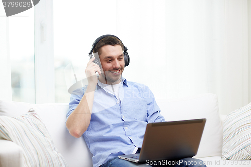 Image of smiling man with laptop and headphones at home