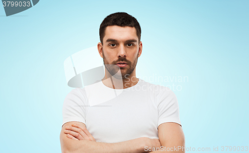 Image of young man with crossed arms over blue background