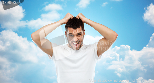 Image of crazy shouting man in t-shirt over blue sky