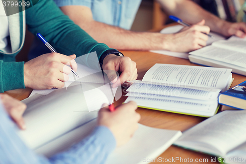 Image of close up of hands with books writing to notebooks