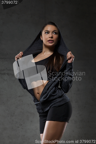 Image of young woman posing and showing muscles in gym