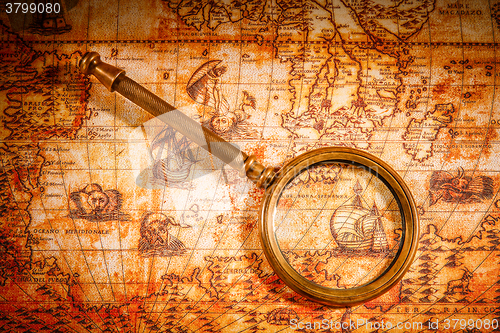 Image of Vintage magnifying glass lies on an ancient world map