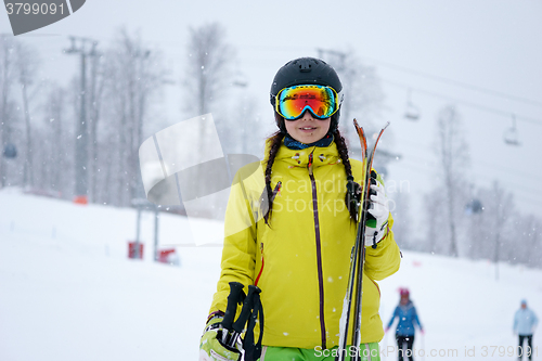 Image of Female skier standing with skies in one hand on background beautiful mountain landscape